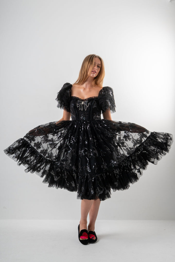 Woman wearing a black lace dress against a white background